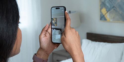 Female measuring bedroom walls with Lowe's Innovation Labs Measure Your Space experience through the Lowe's Home Improvement mobile app.  