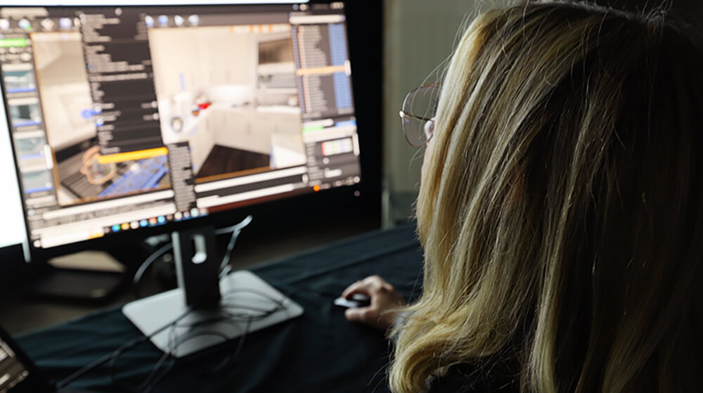 Female Lowes Innovation Labs team member on computer designing kitchen scenes for the Infinite Kitchen Touch experience. 