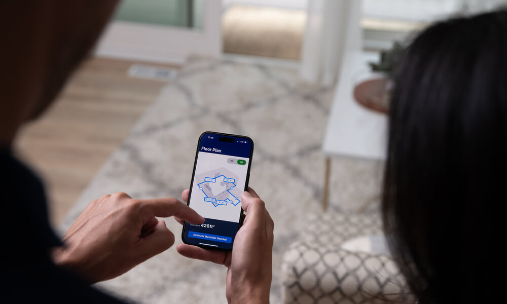 Couple with a mobile device reviewing their room measurements from Lowes Innovation Labs Measure Your Space experience Lowes Innovation Labs Measure Your Space experience.